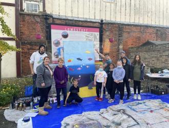 The completed hoardings with members of YMCA Shine and local artist Stane